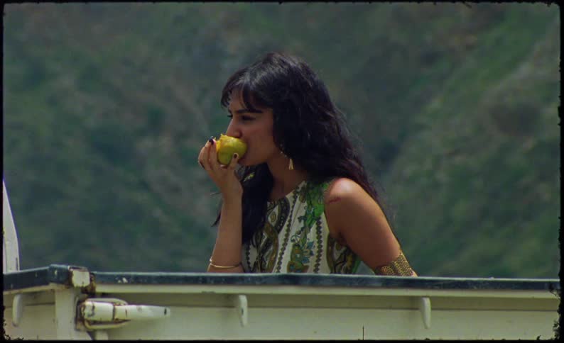 Woman in an outdoor area eating a fruit