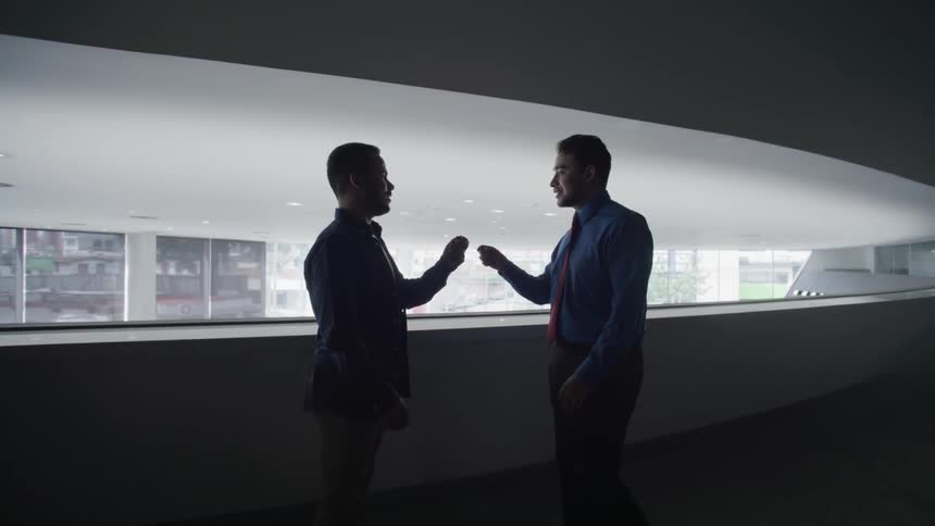 Two men are standing and one of them gives a key to the other and then they shake hands