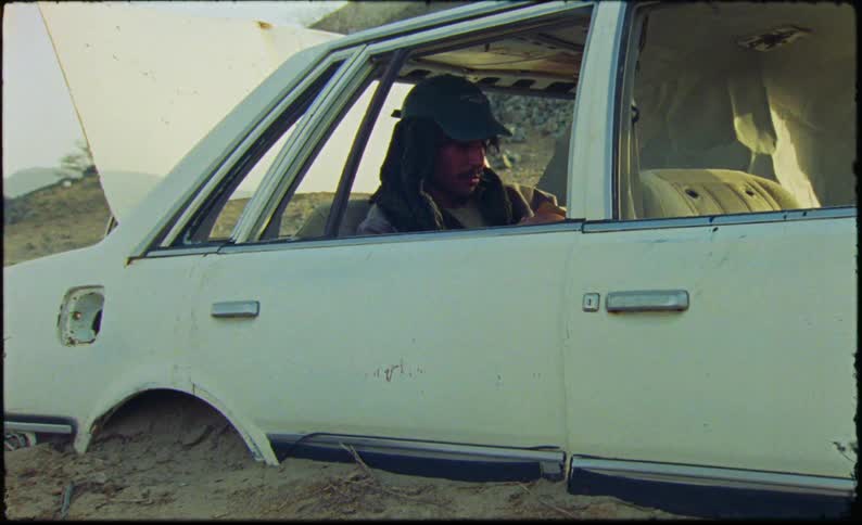 Man sitting in the back seat of a car buried wheeldeep in sand