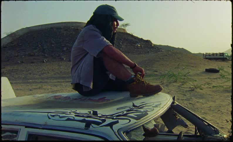 A man is sitting on the roof of a car