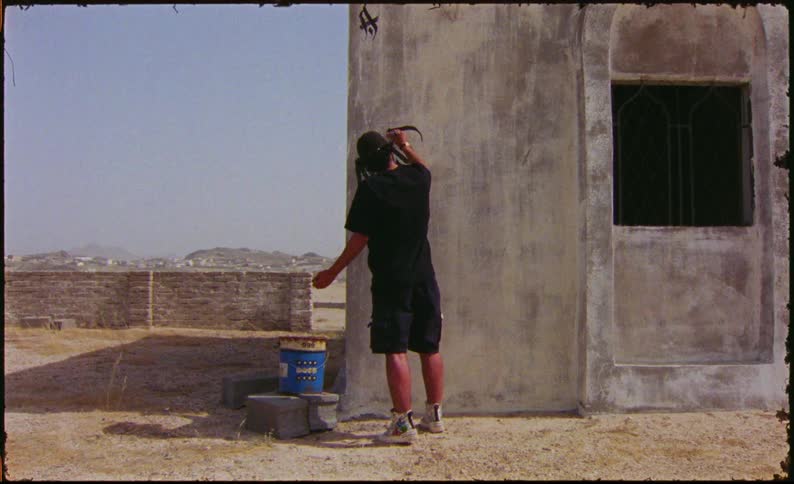 Man graffitiing a wall outdoors