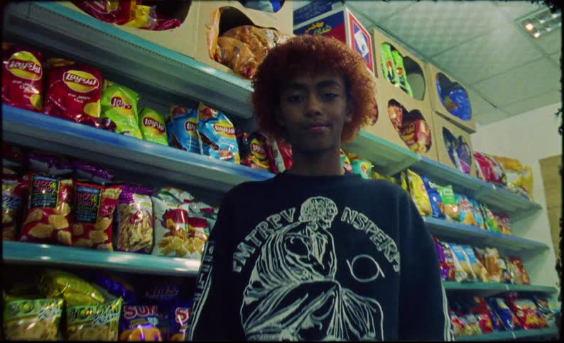 Teenager inside a supermarket with a blue skateboard