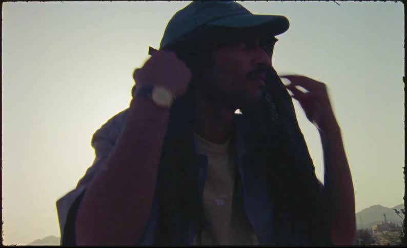 A man puts a scarf then a cap on his head