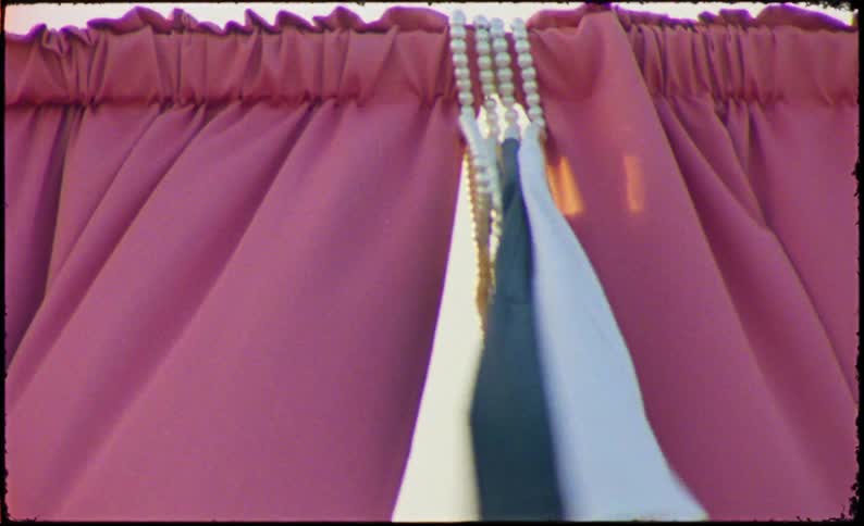 A closeup of red curtains with a decorative tassel hanging in the center