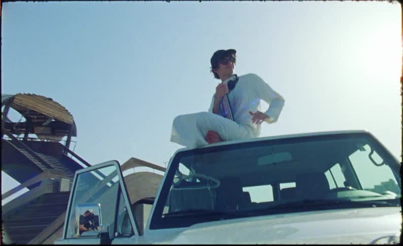 Man sitting on the roof of a car stopped on the side of the highway