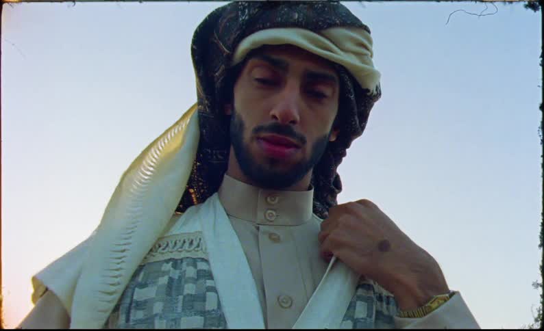 A man is standing outside and wearing a turban