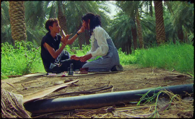 Man and woman sitting on a trail putting on makeup