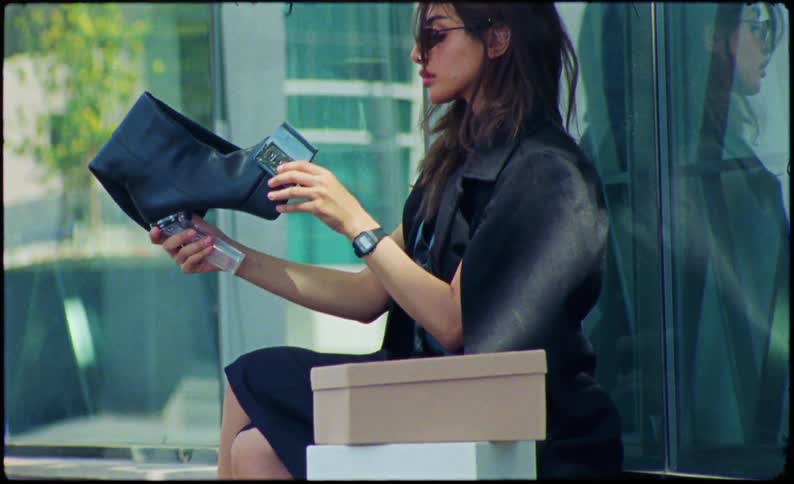Woman with sunglasses sitting looking at high heel boots in an outdoor area