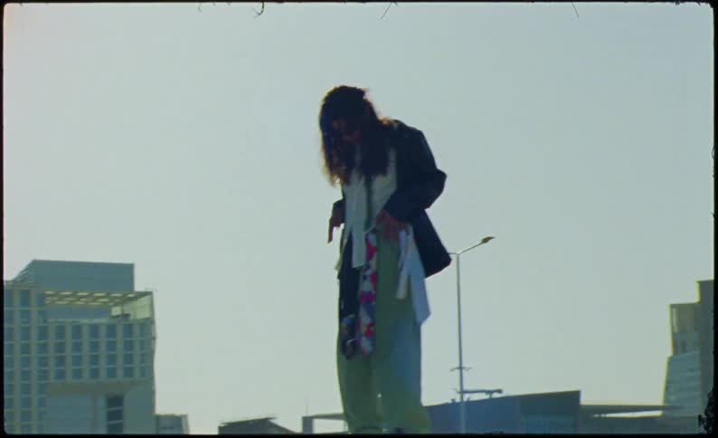 A woman holding her clothes is standing on a concrete block and there is strong sunlight shining on her