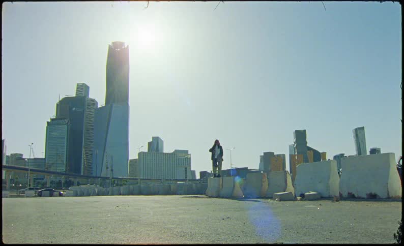 Person standing on a concrete barrier in front of a metropolis