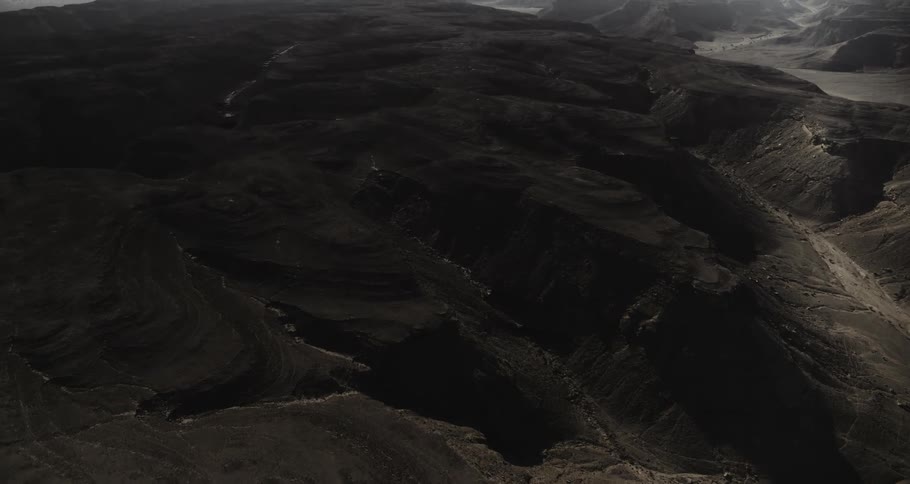 Cinematic Aerial of Alien-Like Desert Terrain with Dark Rocks and Otherworldly Landscapes