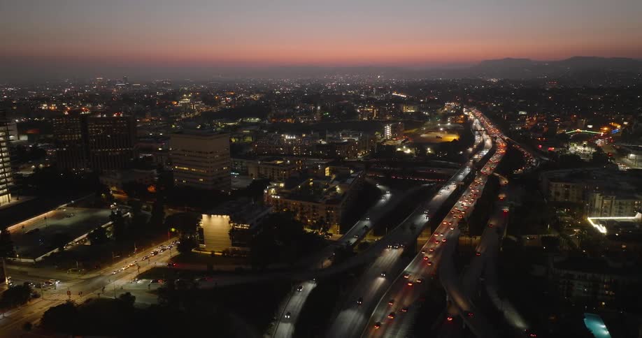 An aerial view of los angeles at night with illuminated streets highways and buildings and a distant mountain range