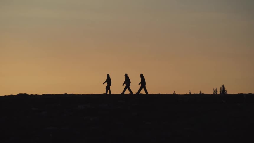 The silhouette of three people walking on a dark morning on flat ground