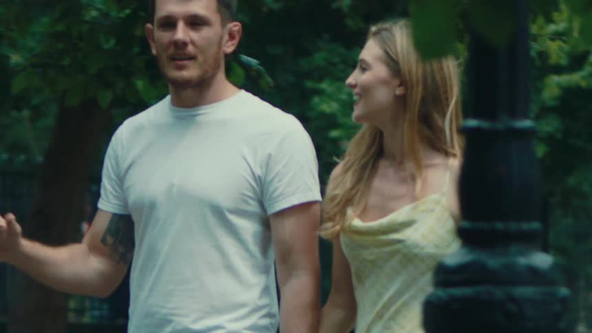 Man and woman walking hand in hand through a park