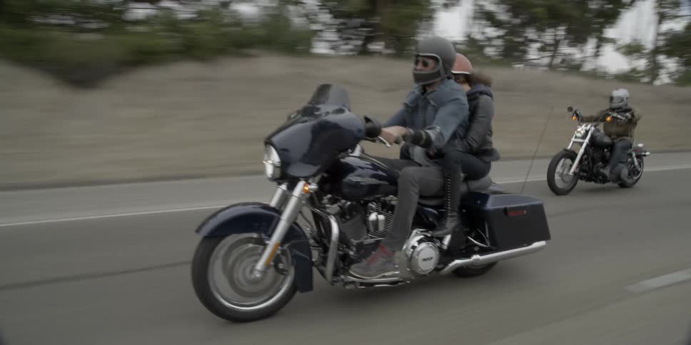 Two people ride down the road on a motorcycle