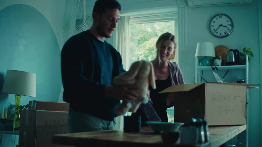 A man pets a stuffed animal as a woman laughs