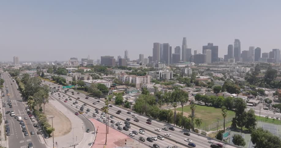 Aerial view of a highway with vehicle traffic in the foreground and a metropolis in the background