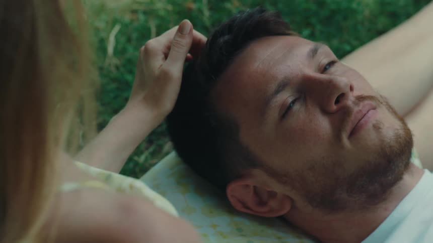 A man is laying in the grass next to a female friend