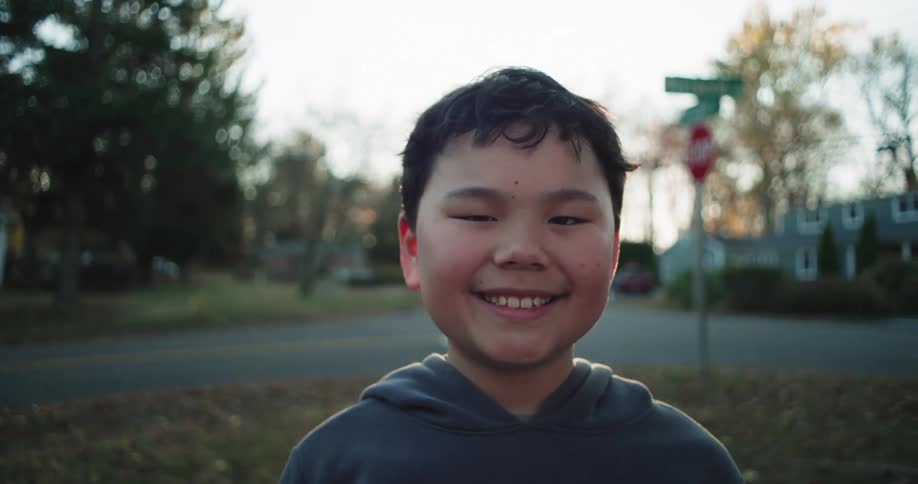 Boy running in a straight direction with houses in the background and the sun on the horizon