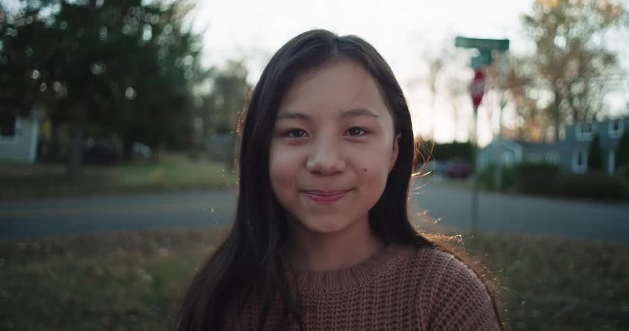 A child is standing on the grass smiling