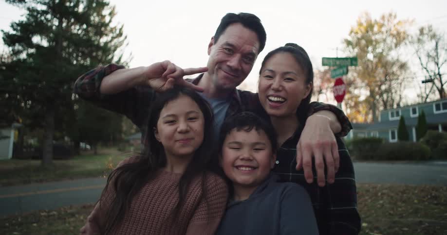 A happy family of four poses together for pictures in their front yard