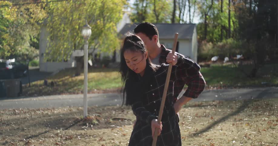 Couple in a backyard happily cleaning during the day