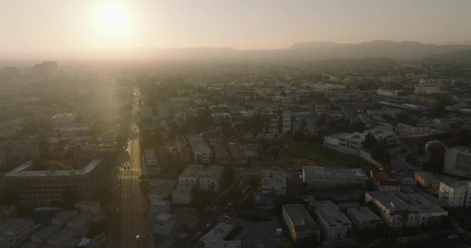 A hazy sunset over a sprawling urban landscape with a distant mountain range