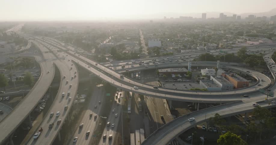 A complex network of highways and interchanges in a large city los angeles with heavy traffic and a hazy atmosphere