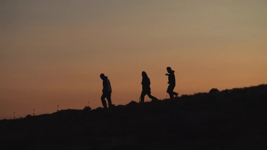 A close up clip of three hikers coming down from the hill