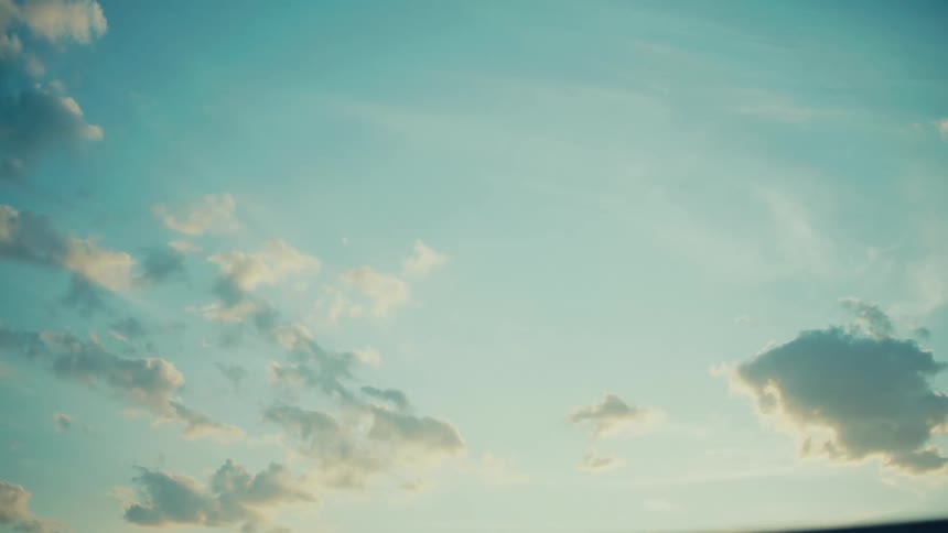A vast expanse of sky with wispy clouds drifting across a gradient of blue and yellow