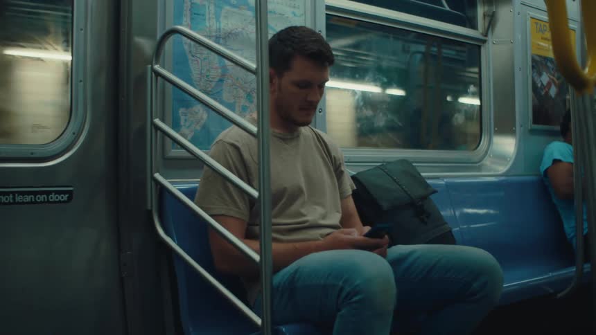 Man sitting on a train interacting with his cell phone