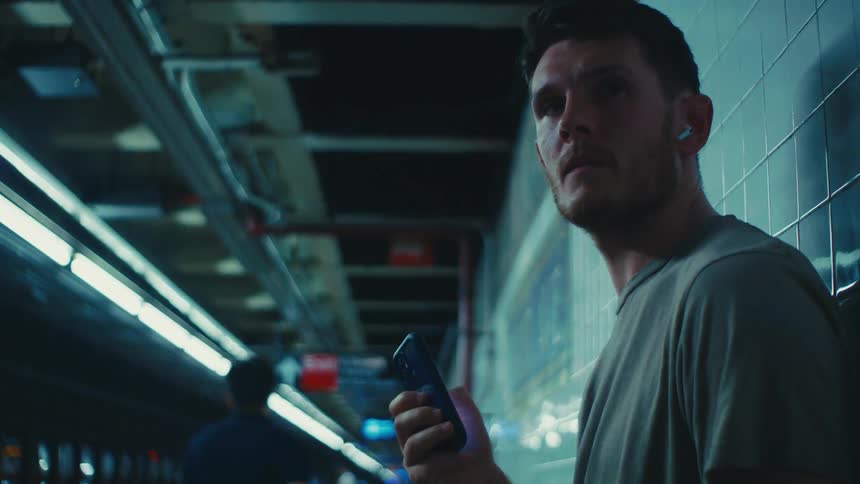 Man interacting with a smartphone while waiting for a train