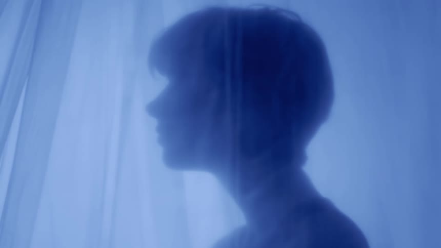 Side portrait of a woman next to a curtain