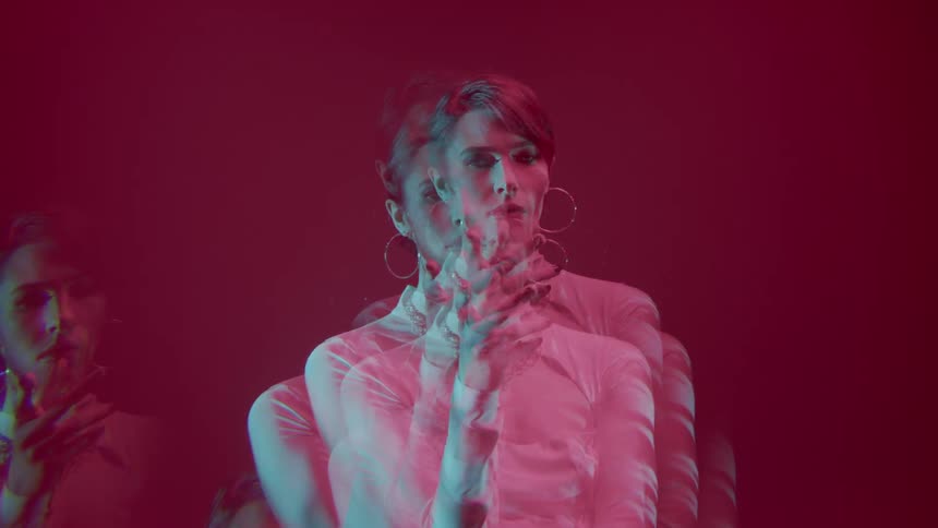 Portrait of a woman in a white dress in multiple exposures against a pink background