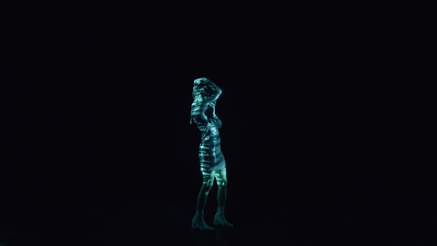 Woman performing in a bright illuminated dress in a dark room