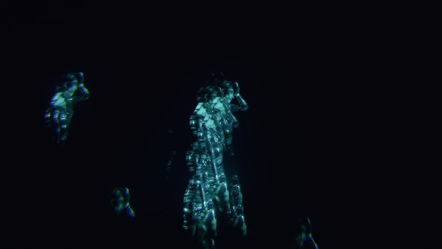 A woman is dancing and covered in blue light