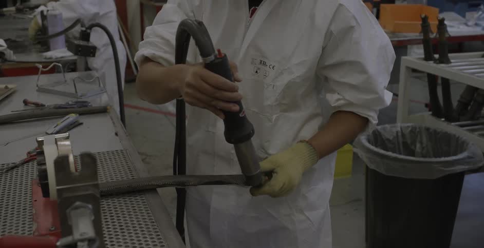 A factory worker smoothes material using a tool