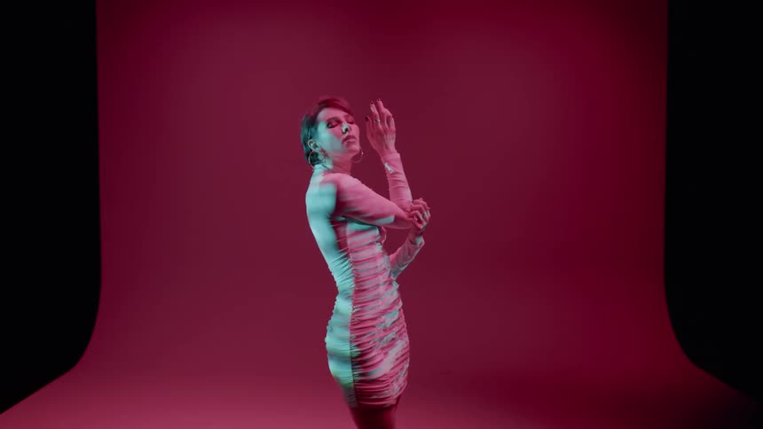 Young woman in white dress in an indoor space against a pink background