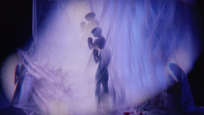 Woman behind curtains at a performance in a dark room