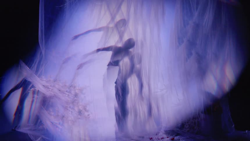Bright lights are flashing behind a curtain where a woman is dancing