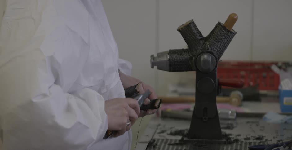 Person wearing a lab cuts an object with scissors