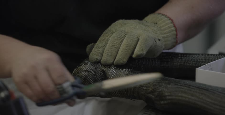 A person uses scissors to trim metal mesh