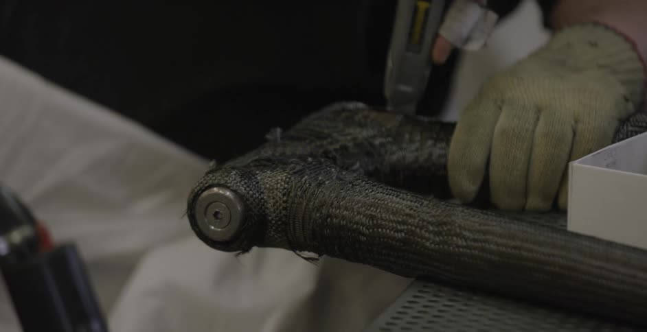 A man uses a utility knife to trim metal mesh