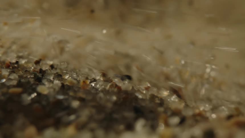 The floor of a small stream of clear water with several crystallized pebbles moving with the current