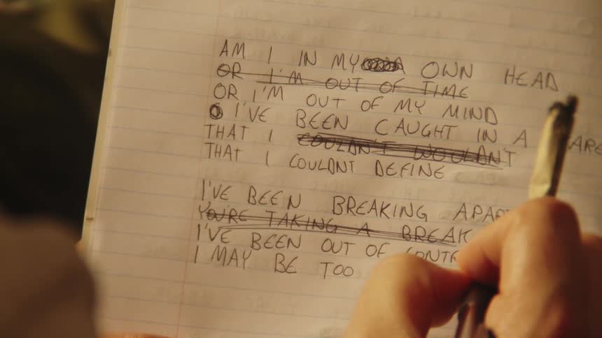 A close clip of a person writing while holding a smoke