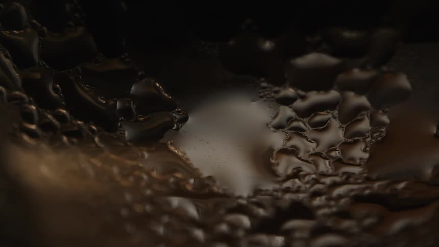 A dark textured surface with a pattern of raised bubbles in a rich dark liquid