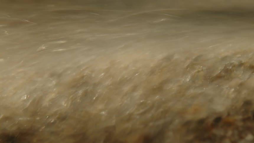 A small wave of a transparent liquid with a brownish color and is moving slowly