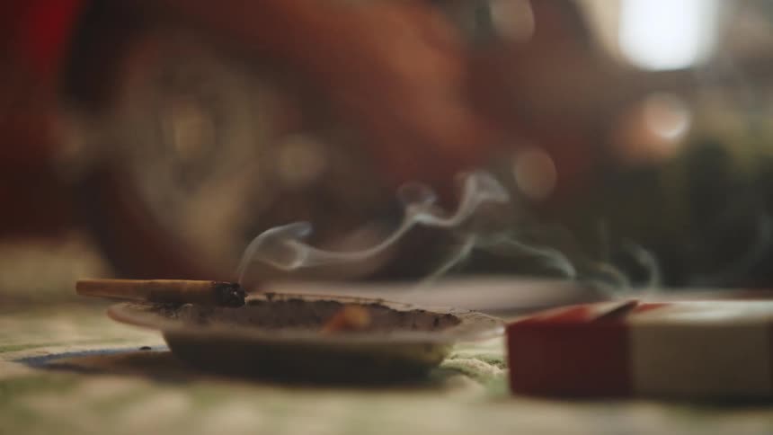 Shaking ashes off a joint and setting it on an ashtray