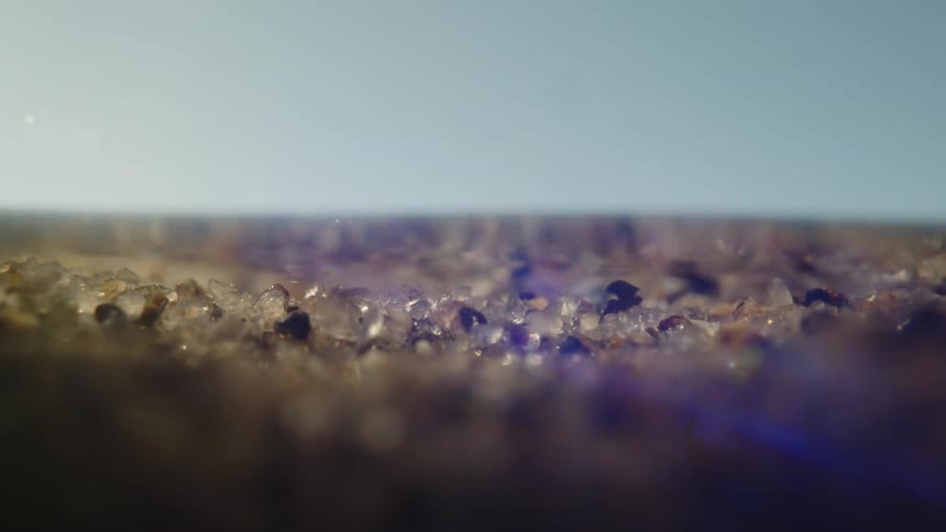 Several crystal colored stones are moving to the right and there is a strong blue light hovering over the environment