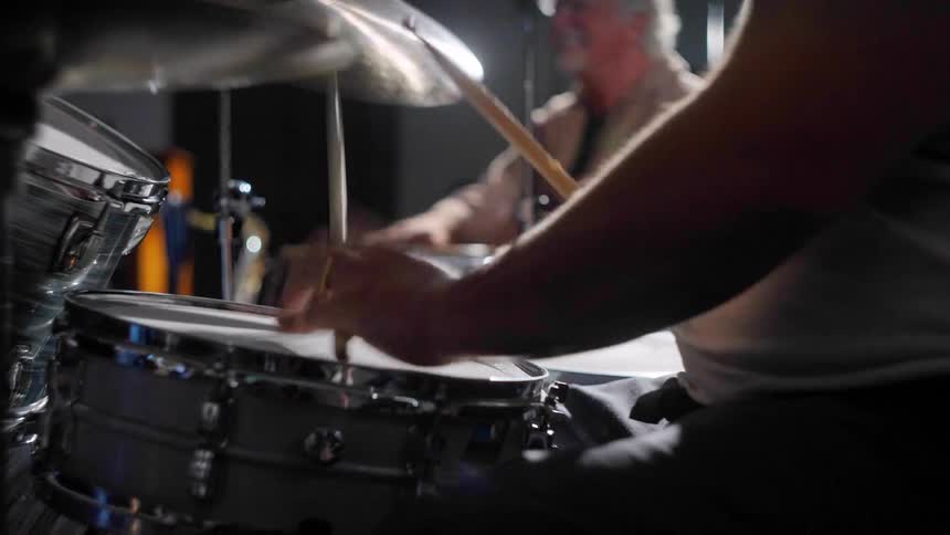 Two men sitting playing drums